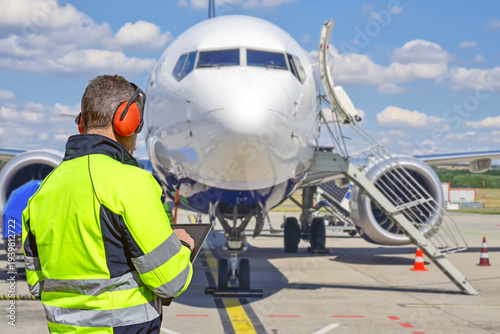 Airport ground crew worker using tablet during aircraft ground handling.