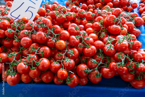 Large pile of fresh vine tomatoes with price tag at a farmer's market