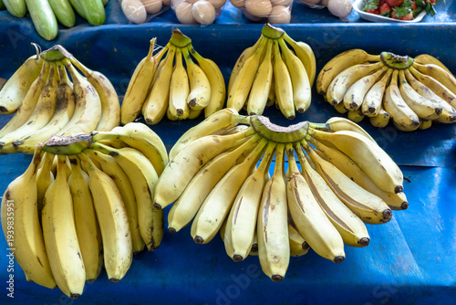 Fresh bunches of local bananas displayed on a blue market counter