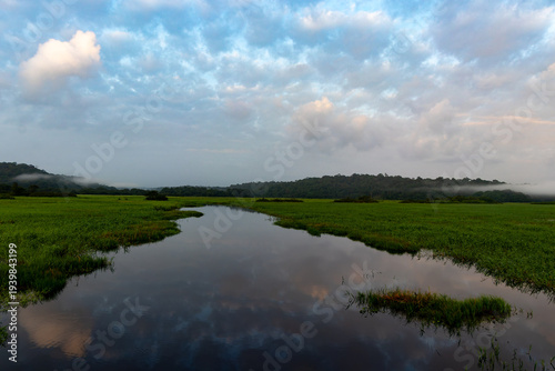 Sunrise and sunset over Kaw wetlands, traditional canoes on calm water, tropical marsh in French Guiana.