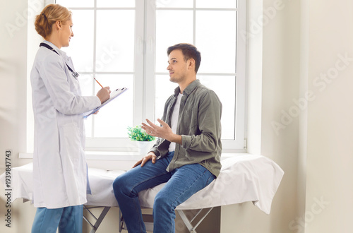 Tablou pe pânză Patient explains health problems and attentive doctor writes down information during consultation