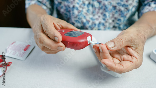 Foto Close up of senior woman using blood glucose meter for diabetes test at home