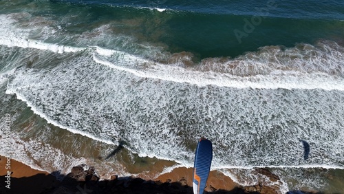 Paraglider flying over the beach near a headland in Sydney Australia 