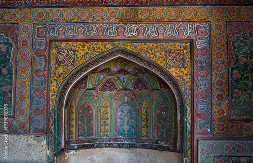 Close-up of intricate frescoes and kashi-kari tile work inside Wazir Khan Mosque, Lahore, Pakistan. This stunning Mughal artwork features vibrant colors and floral patterns.
