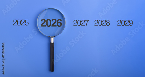 Magnifying glass highlighting the year 2026 representing planning, goal setting, deadlines, and important upcoming events with focus on future achievements and targets.