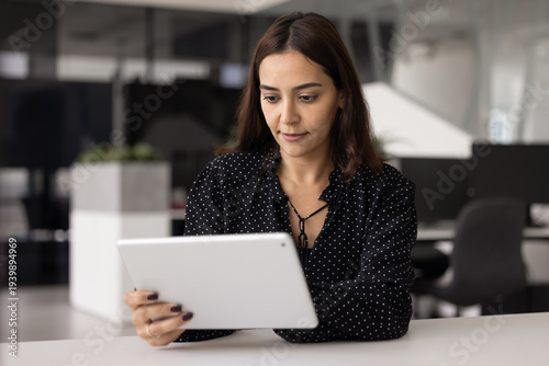 Serious beautiful Middle Eastern professional woman using business application, financial online service on tablet for work, typing on digital pad at office workplace, browsing Internet Free Download Serious beautiful Middle Eastern professional woman using business application, financial online service on tablet for work, typing on digital pad at office workplace, browsing Internet - GFXLoad