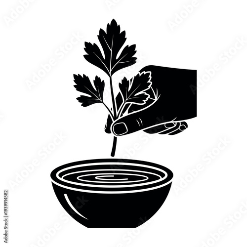 Hand dipping parsley into a bowl of liquid.