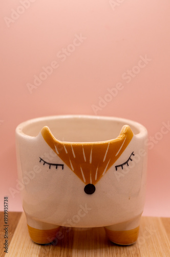 Subject shot of funny ceramic pot made as funny cartoon fox. Bright plant pot for interior design is isolated on the white background.