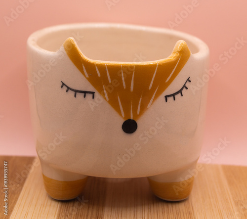 Subject shot of funny ceramic pot made as funny cartoon fox. Bright plant pot for interior design is isolated on the white background.