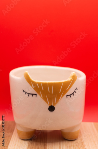 Subject shot of funny ceramic pot made as funny cartoon fox. Bright plant pot for interior design is isolated on the white background.