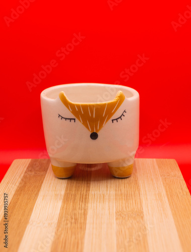 Subject shot of funny ceramic pot made as funny cartoon fox. Bright plant pot for interior design is isolated on the white background.