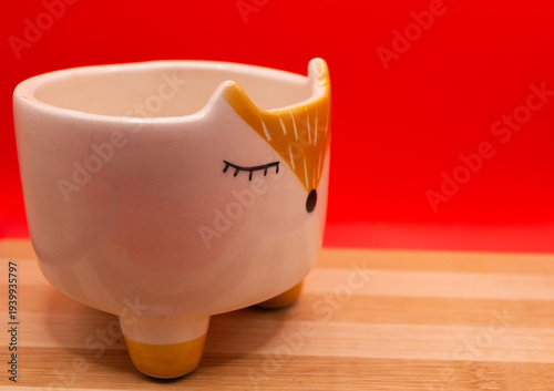 Subject shot of funny ceramic pot made as funny cartoon fox. Bright plant pot for interior design is isolated on the white background.