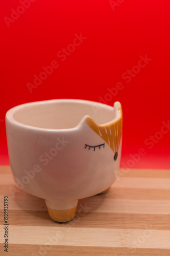 Subject shot of funny ceramic pot made as funny cartoon fox. Bright plant pot for interior design is isolated on the white background.