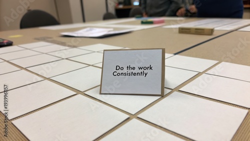 Motivational Card on Table with Text Encouragement for Consistent Work in Collaborative Workspace Setting