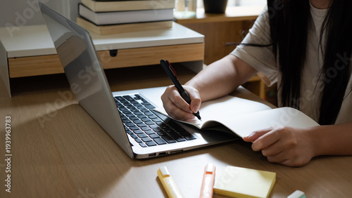 Tableau sur toile Remote worker writing notes during virtual meeting on laptop, Student studying f