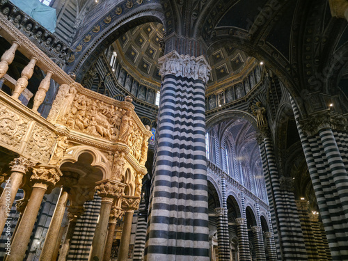 Interior of Siena Cathedral featuring Nicola Pisano's Gothic pulpit, striped marble columns and the ornate dome, Tuscany, Italy