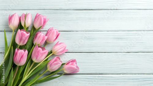 Pink tulips arranged on a light wood surface in a simple setting during daytime