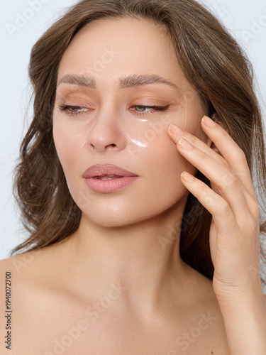 Fotografie Enhancing Natural Beauty: A Woman Applying Hydrating Skincare Patches for Radian
