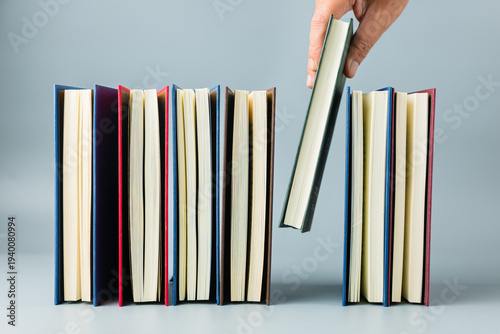 Hand taking book from row of books representing learning and knowledge search