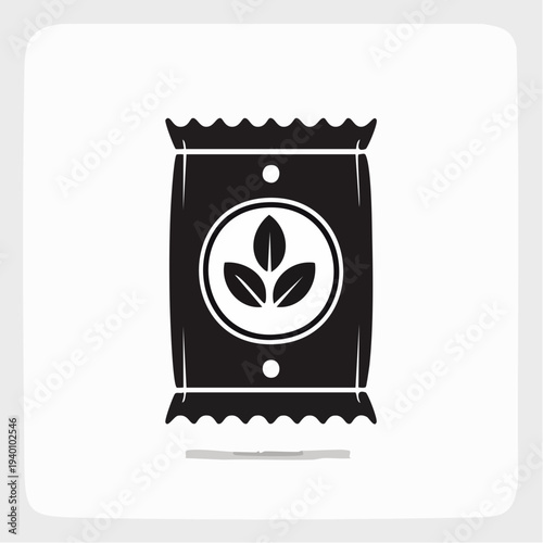 A simple black and white icon representing a packet of seeds with a plant logo and a shadow underneath