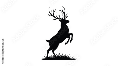 Silhouette of a majestic stag with large antlers standing on a patch of grass seen from the side against a solid white background area.