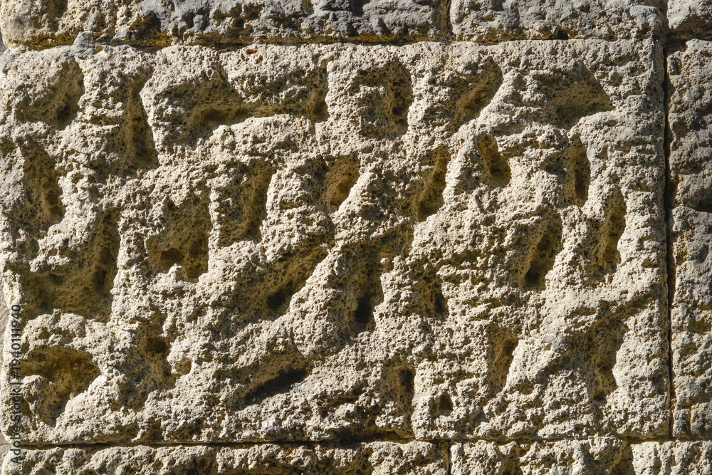 Ταπετσαρία A close up view shows the rough and weathered surface of an ancient stone block