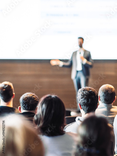 Speaker giving a talk in conference hall at business event. Rear view of unrecognizable people in audience at the conference hall. Business and entrepreneurship concept