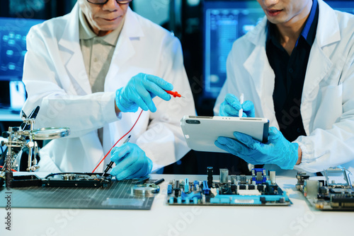 Engineers repairing computer hardware and analyzing data storage systems in a high-tech lab with cybersecurity monitoring, diagnostics, and digital technology