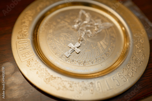 Silver orthodox cross on golden liturgical plate in church interior
