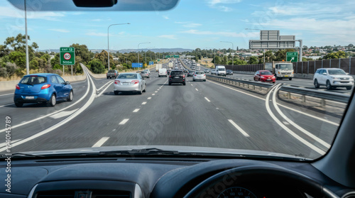 A driver gazes out at steady highway traffic, framed by a vast, clear blue sky. A quiet moment of journey and motion, evoking freedom and the open road.