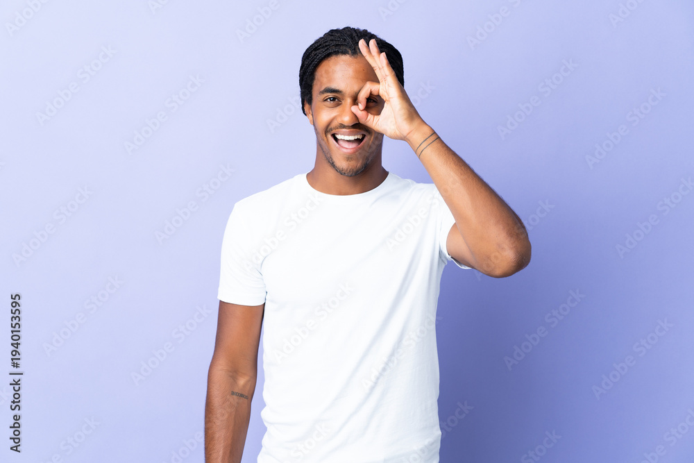 Naklejka premium Young African American man with braids man isolated on purple background showing ok sign with fingers