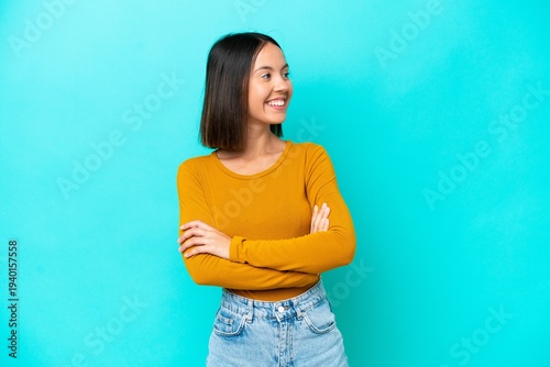 Young caucasian woman isolated on blue background looking to the side
