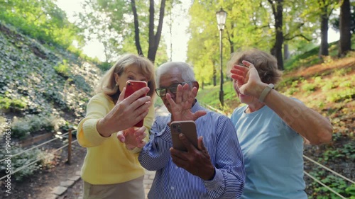 Elderly persons display surprise and cheerfulness on park video call. Senior individuals exhibit lively reactions and waving gestures during outdoor digital communication session