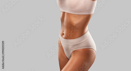 Tableau sur toile A slender swarthy woman in beige underwear on a dark background