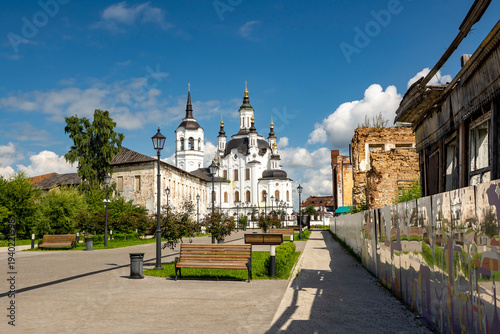 A street in a recreation park in a small Siberian town, bathed in autumn sunshine. At the end of the street is a church. Tourism in Russia
