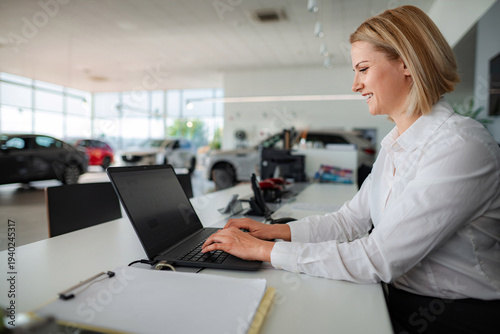 Photos Woman sales manager working on laptop in car dealership