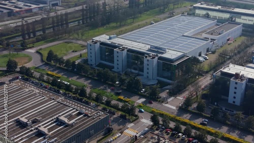 Industrial Park Aerial View: An expansive aerial view showcases a modern industrial park with sleek, contemporary buildings and vast parking lots, Assago, Milan