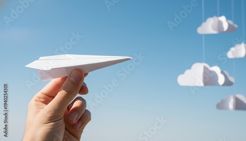 Paper airplane, Hand, Sky, Cloud, Freedom, Launch, Future conceptual image of a person's hand holding a paper plane against a blue sky with paper clouds representing business startup.
