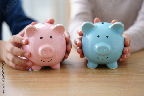 Two piggy banks pink and blue held by hands saving