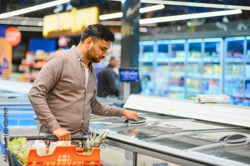 Cuadro en lienzo Man shopping for frozen food in supermarket aisle