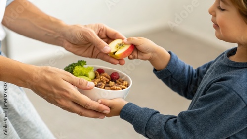 Adult hands offering a bowl of granola with fruit to a smiling child, sharing a healthy snack in a cozy home setting.