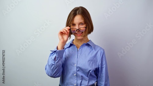 Beautiful girl taking off glasses for vision winking playful young woman removing eyeglasses flirty expression fun interaction with camera studio portrait optics