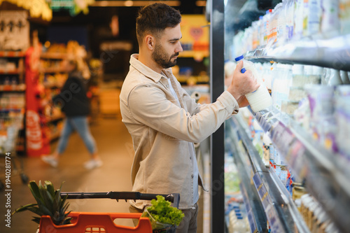 Cuadro en lienzo Man buying milk from supermarket dairy aisle