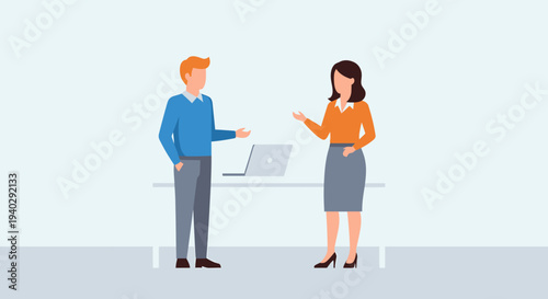 Two professionals engaged in a discussion at a desk with a laptop in a modern office environment from a slightly angled viewpoint