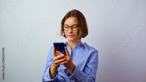 Girl putting on glasses for vision to better see mobile phone screen due to poor vision young woman with bad eyesight using smartphone with eyeglasses studio