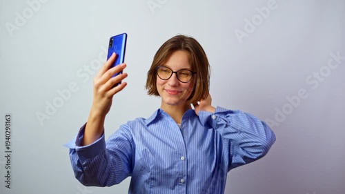 Girl taking selfie posting on phone rejoicing purchase of new glasses happy young woman celebrating new eyeglasses on social media joy success studio