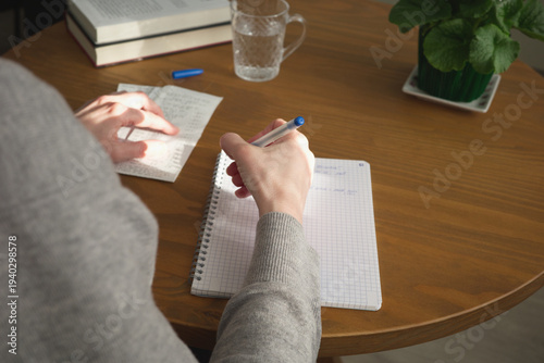Woman checking bills taking down notes household budget conceptual photo