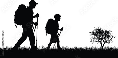 Black silhouette of father and young son with backpacks and trekking poles hiking through grass field at sunset during a family outdoor summer mountain adventure
