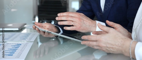 Foto Business partners collaborating on financial data, discussing market trends, analyzing charts, and reviewing reports on a tablet during an office meeting