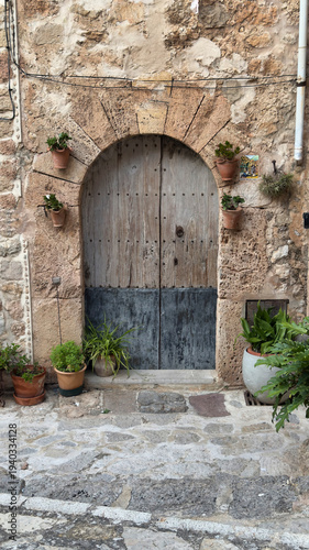 Traditional Stone Archway with Wooden Door and Flower Pots in Valldemossa, Mallorca